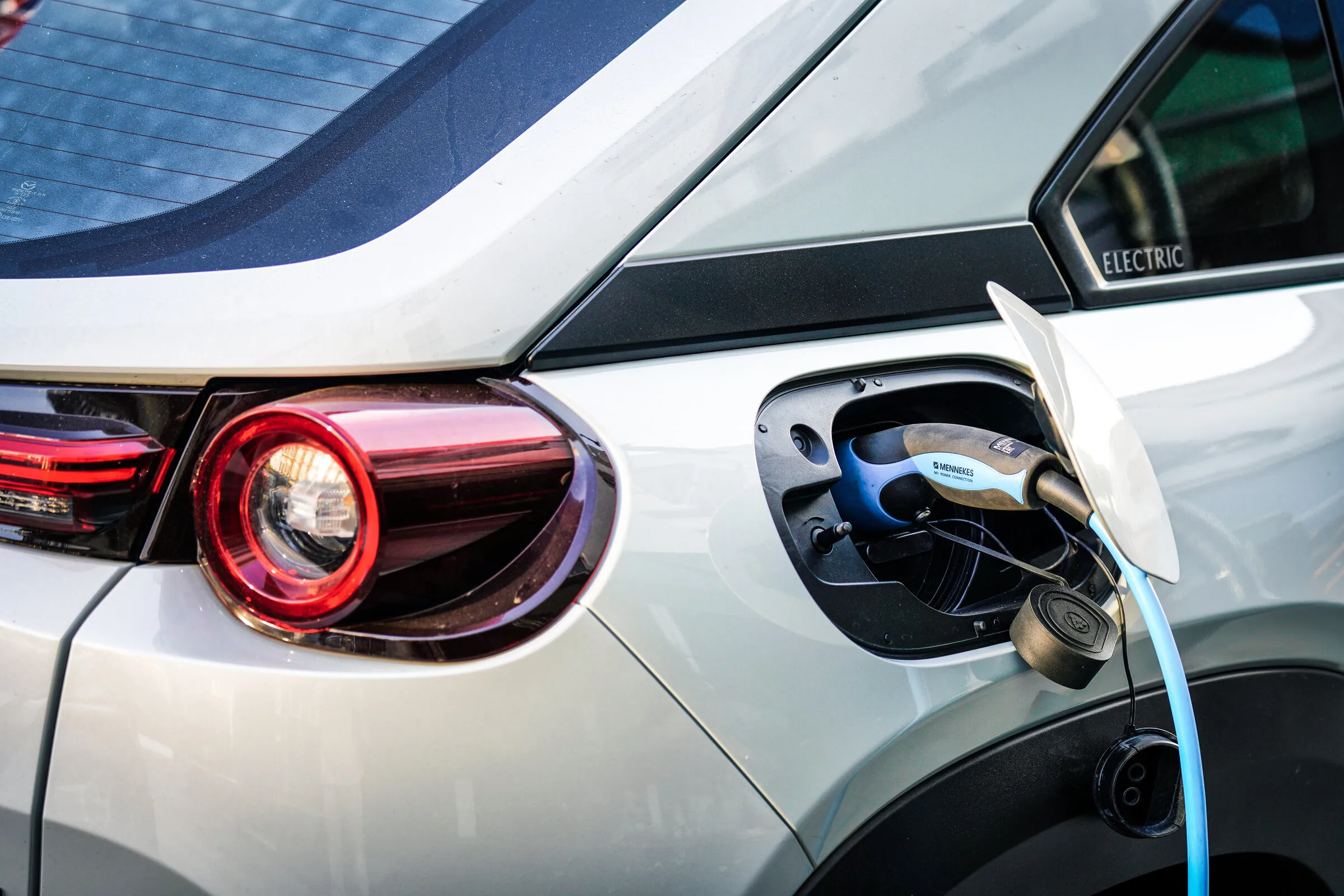 Close-up of an EV charging connector plugged into a white electric vehicle