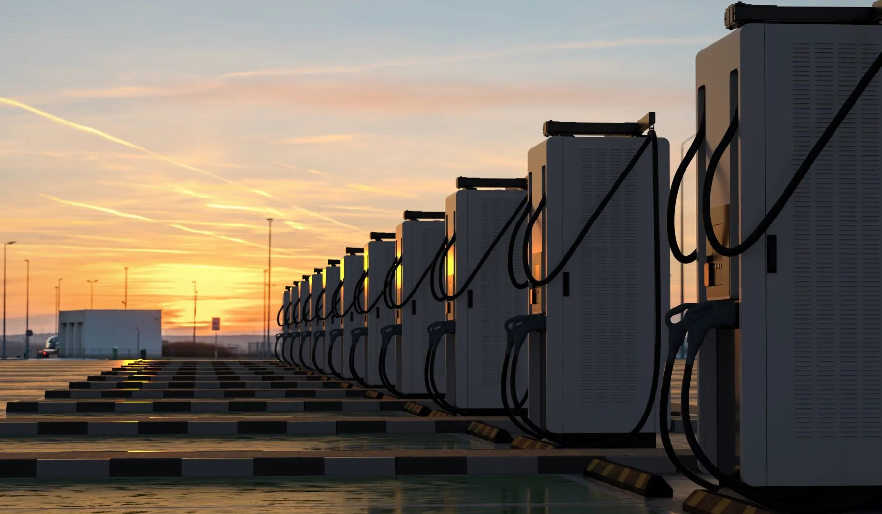 A long row of electric vehicle fast chargers at sunset